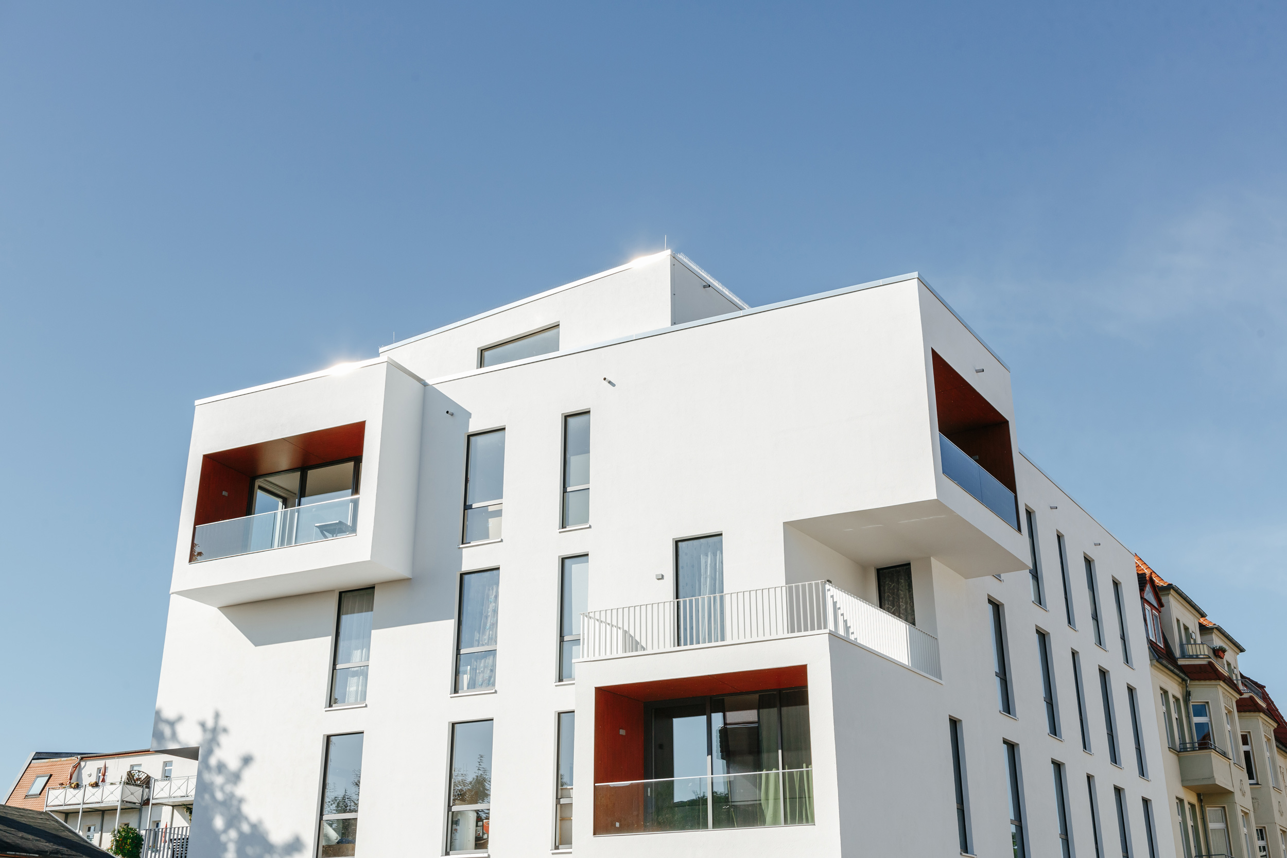 Modernes Mehrfamilienhaus mit großen Balkonen und klaren Linien.