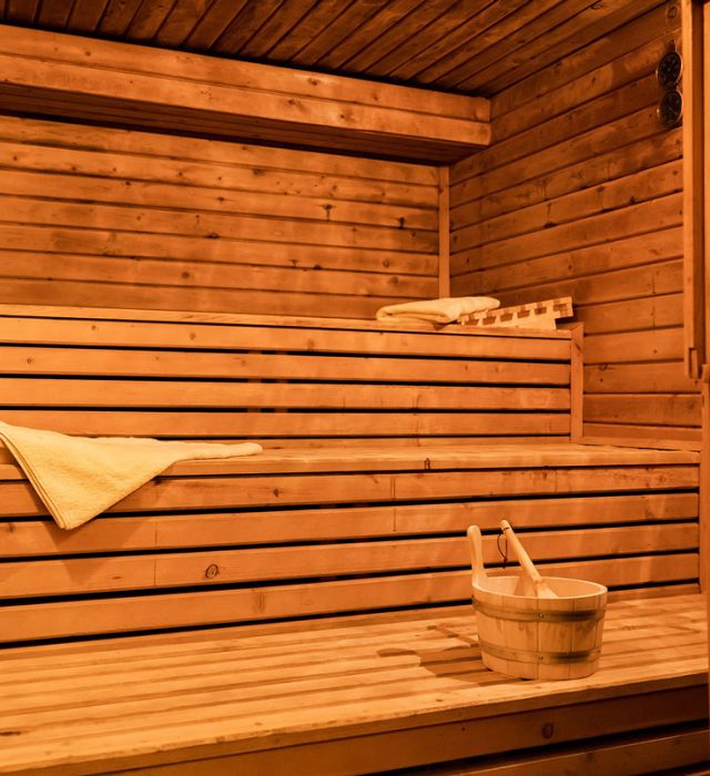 Gemütliche Holzsauna mit Handtüchern und Aufgusskübel – perfekter Ort zur Entspannung und Erholung für Körper und Geist.