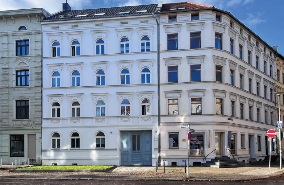 Historisches Stadthaus mit renovierter Fassade und blauer Eingangstür an einer Straßenecke.