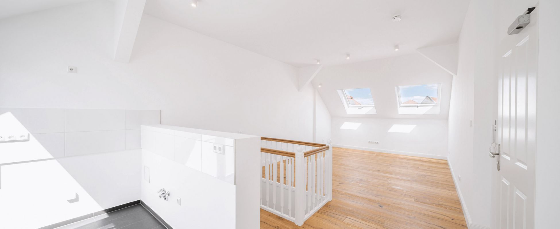 Heller, moderner Dachboden mit Holzboden und eingebauten Fenstern.