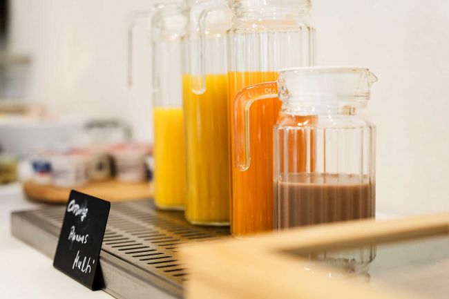 Frühstücksbuffet mit frischen Säften – Orangensaft, Multivitamin und Kakao in stilvollen Glaskaraffen für den perfekten Start in den Tag.