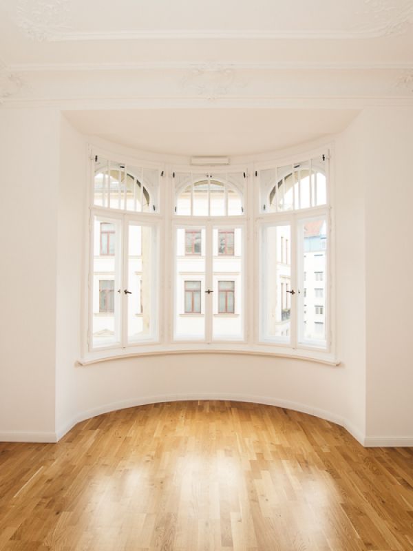 Elegantes Altbauzimmer mit geschwungenem Erkerfenster, Stuckdecke und edlem Parkett für lichtdurchflutetes Wohnambiente.