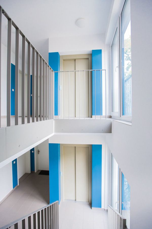 Helles, mehrstöckiges Treppenhaus mit blauen Akzenten und großen Fenstern.