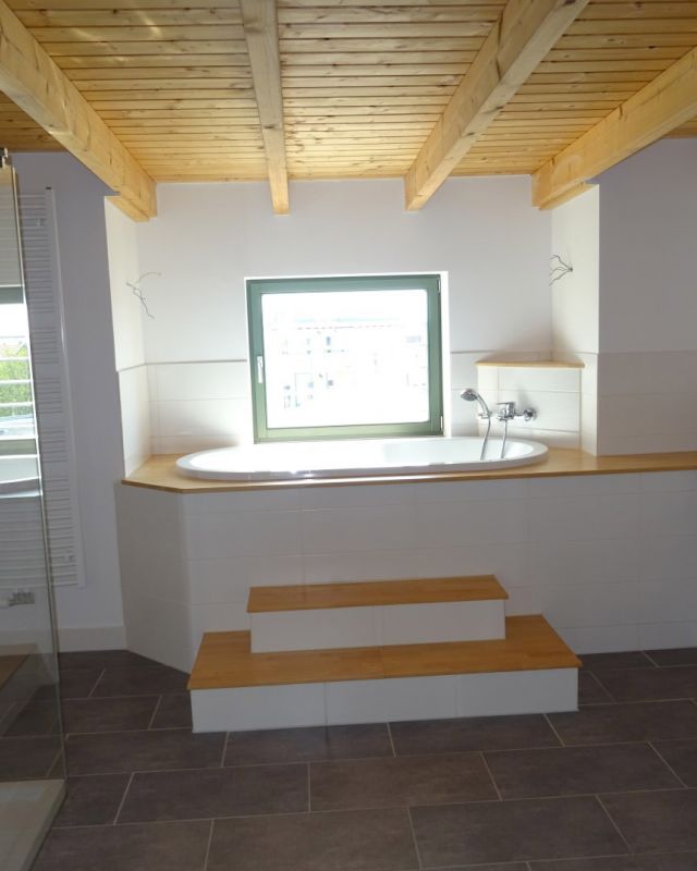 Helles Badezimmer mit freistehender Badewanne, Holzdecke und moderner Dusche – stilvolle Wellness-Oase mit Tageslicht.