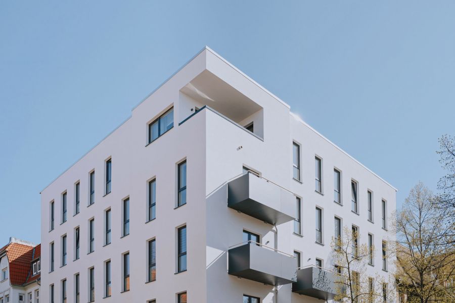 Modernes Mehrfamilienhaus mit klaren Linien und Balkonen unter blauem Himmel.