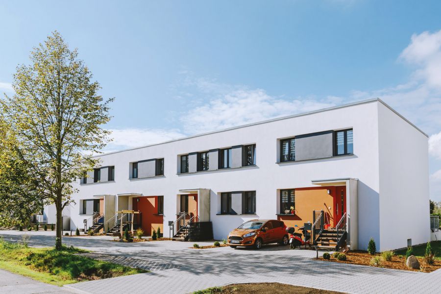 Moderne Reihenhäuser mit farbigen Eingängen unter blauem Himmel.