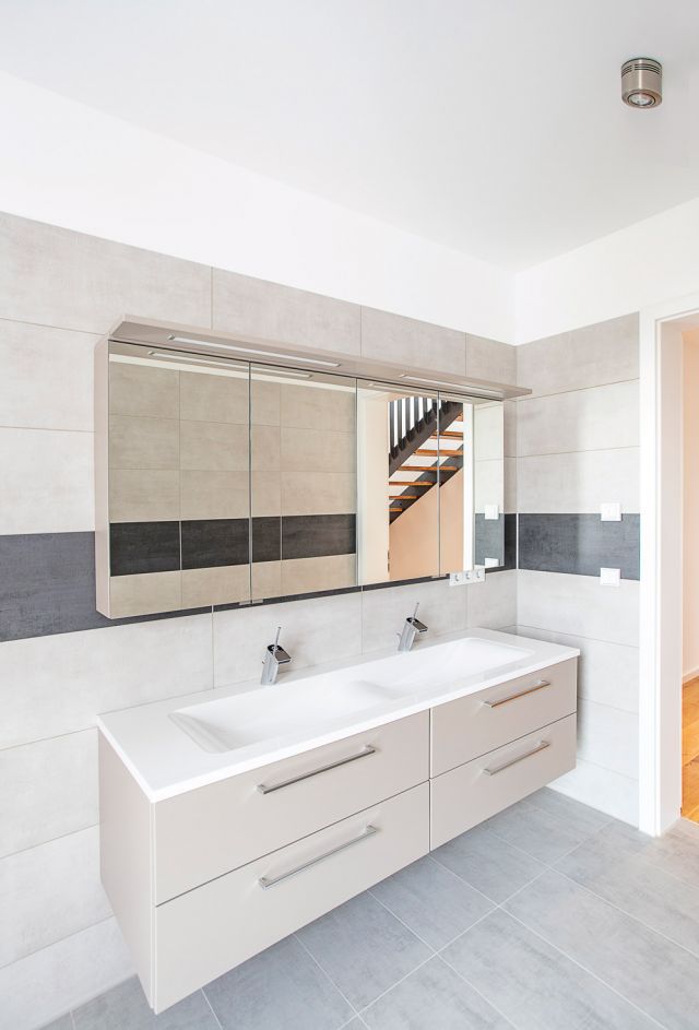 Modernes Badezimmer mit großer Spiegelwand und eleganten grauen Fliesen.