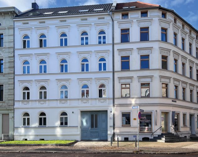 Historisches Stadthaus mit renovierter Fassade und blauer Eingangstür an einer Straßenecke.