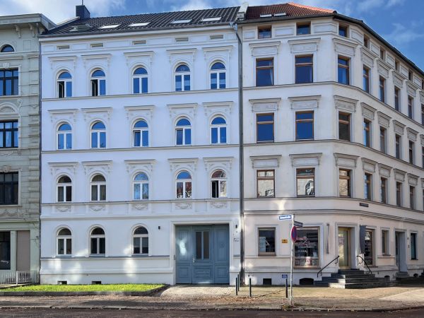 Historisches Stadthaus mit renovierter Fassade und blauer Eingangstür an einer Straßenecke.