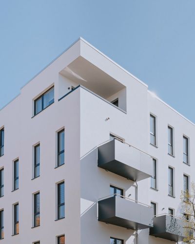 Modernes Mehrfamilienhaus mit klarer Architektur, großen Fenstern und Balkonen.