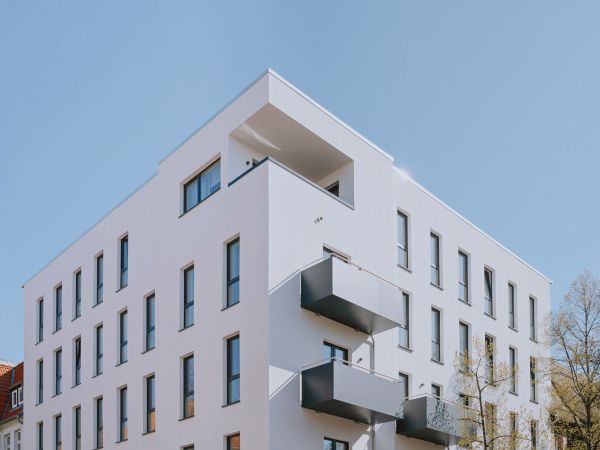 Modernes Mehrfamilienhaus mit klarer Architektur, großen Fenstern und Balkonen.