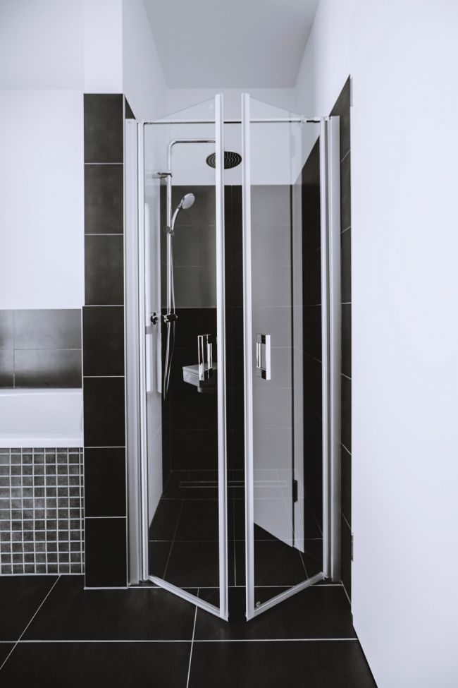 Modernes Badezimmer mit Eckschrankdusche und eleganter schwarz-weißer Fliesenoptik.