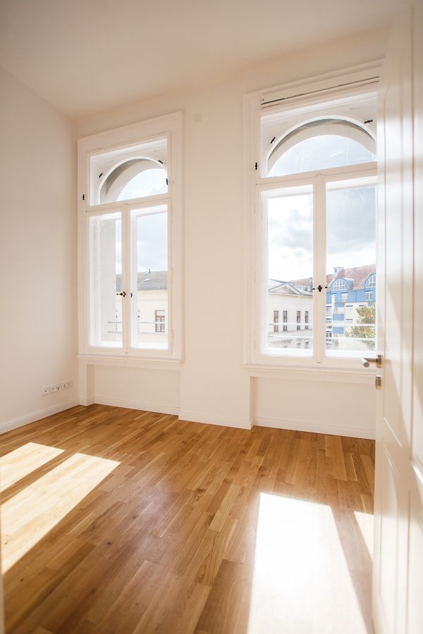 Helles Altbauzimmer mit großen, historischen Fenstern und elegantem Parkettboden, durchflutet von natürlichem Licht.