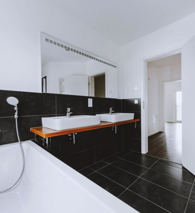 Stilvolles Badezimmer mit schwarzen Fliesen, Doppelwaschbecken und Holzakzenten.