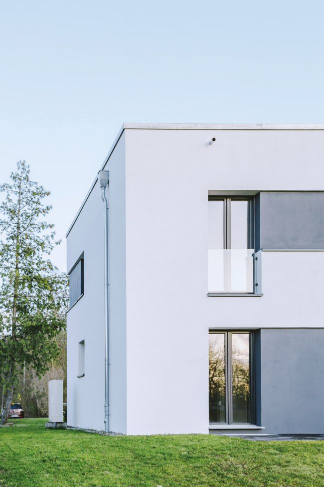 Minimalistisches modernes Gebäude mit großen Fenstern und umgebendem Grünbereich.