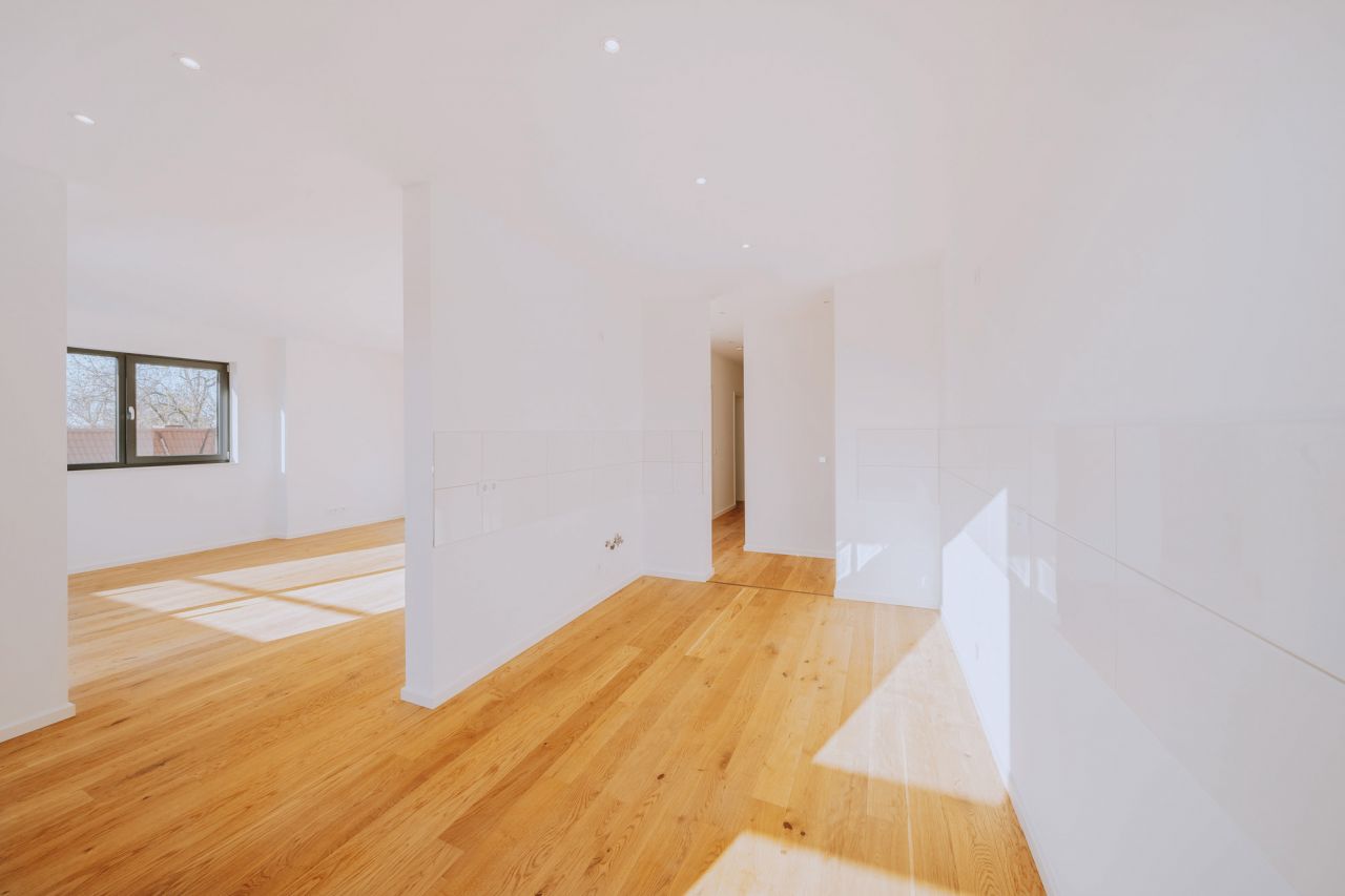 Helles, offenes Wohnkonzept mit Holzfußboden und vorbereiteter Küchenzeile.